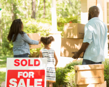 Family holding boxes moving into new home