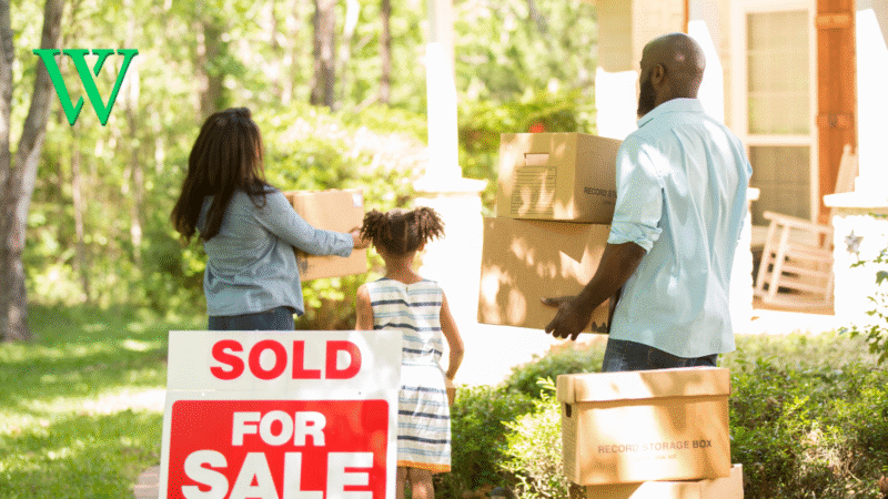 Family holding boxes moving into new home