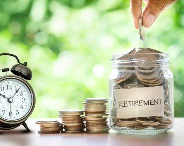 green background with alarm clock, various stacks of coins, and a jar filled with coins labeled "retirement" on a table